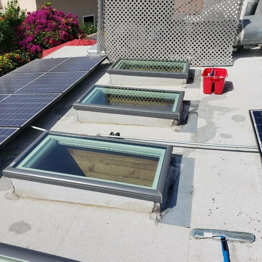 Solar skylight window cleaning on a building rooftop with solar panels.