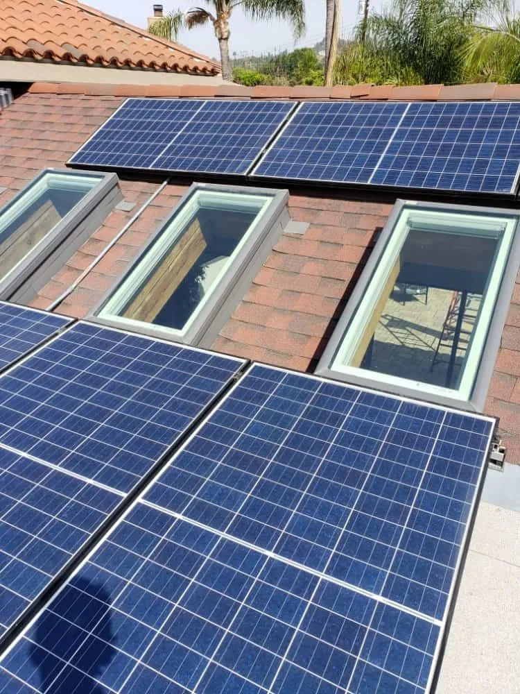 Solar panels on a house roof with skylights, freshly cleaned and shining.