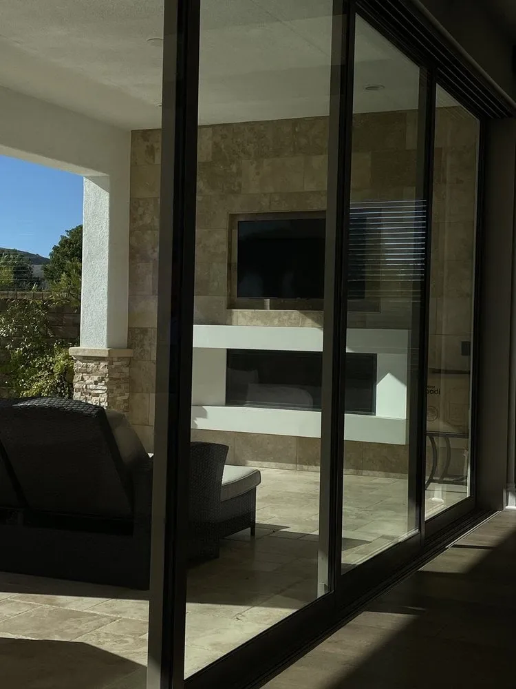 Glass sliding door leading to a stylish living room with a TV and modern decor.